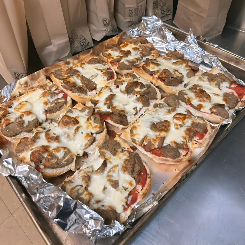 A tray of U-Know Pizza & Sandwich Shop's mini pizzas with melted cheese and meat.